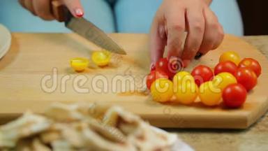 一个女人正在用一把刀切一个黄色和红色的樱桃番茄